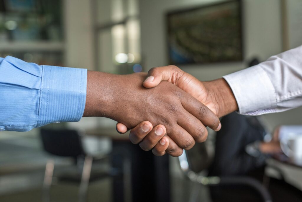 pexels-photo-955395-955395 Close-up of two men's handshake symbolizing agreement in an office.